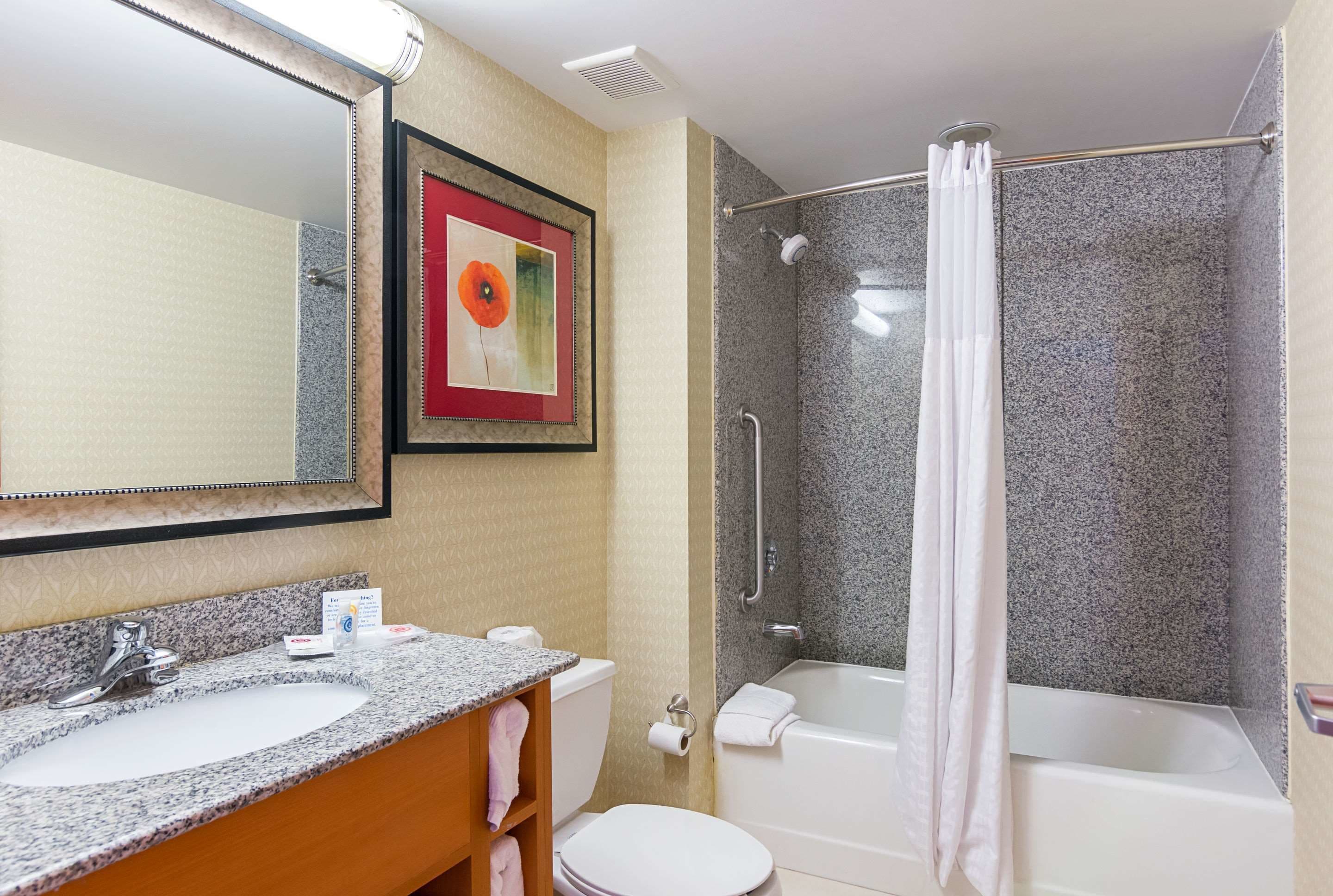Un baño con lavamanos de encimera de granito, inodoro, bañera y ducha con puerta de cristal.