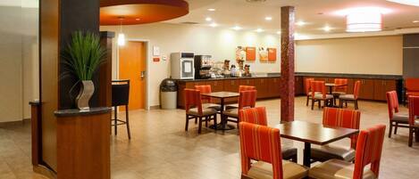 En hotellobby med en receptionsdisk, en sittgrupp och ett litet pentry.