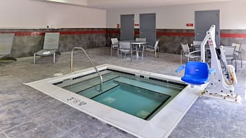 An indoor swimming pool with a tiled floor, a pool table, and several chairs.