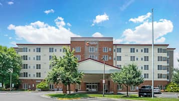 Situated on a street corner, this hotel features a flat roof and a brick facade, surrounded by a well-maintained lawn with trees.