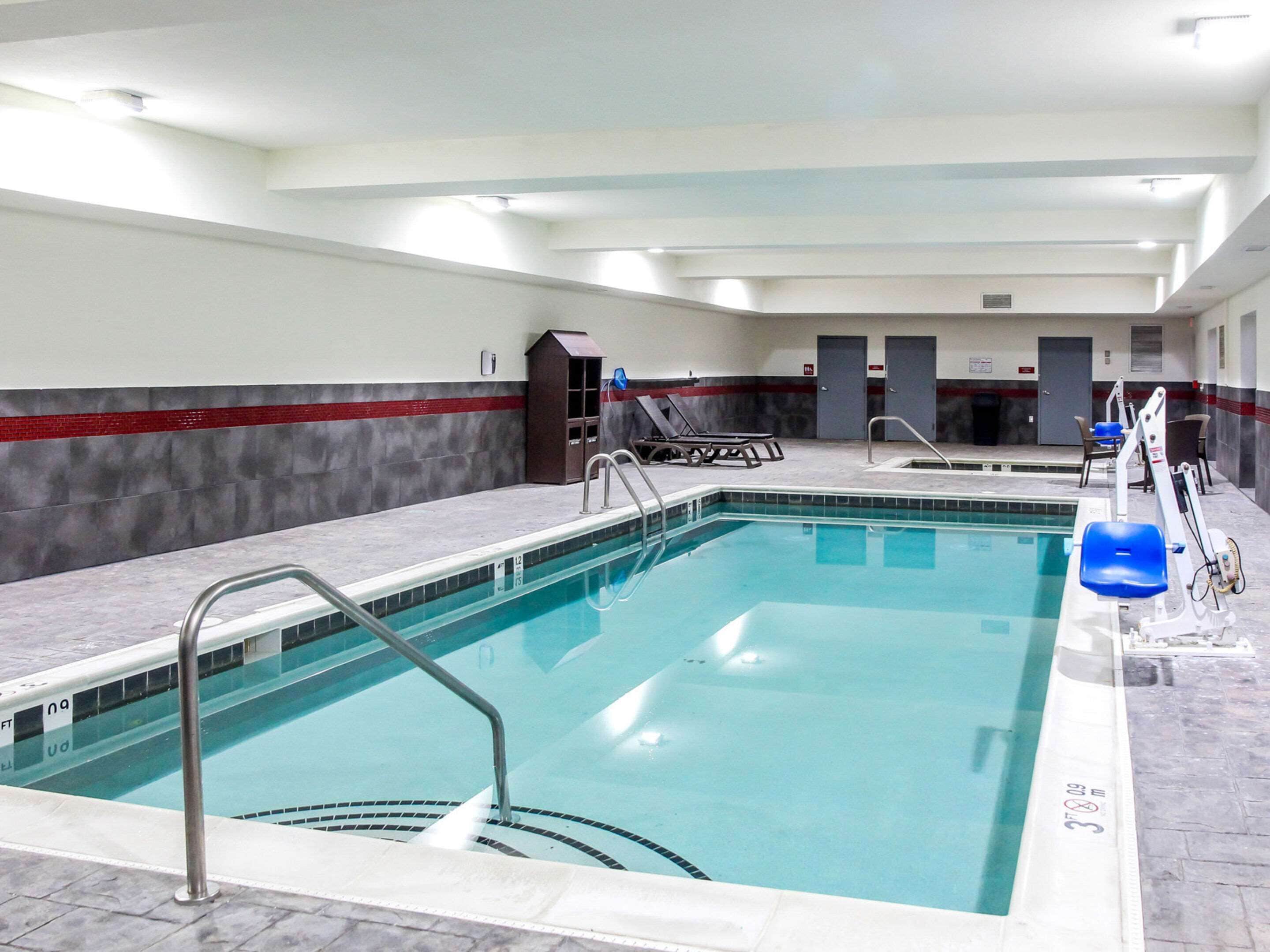 Une piscine intérieure avec des lignes de démarcation bien visibles, un poste de surveillance pour les sauveteurs et des chaises longues.