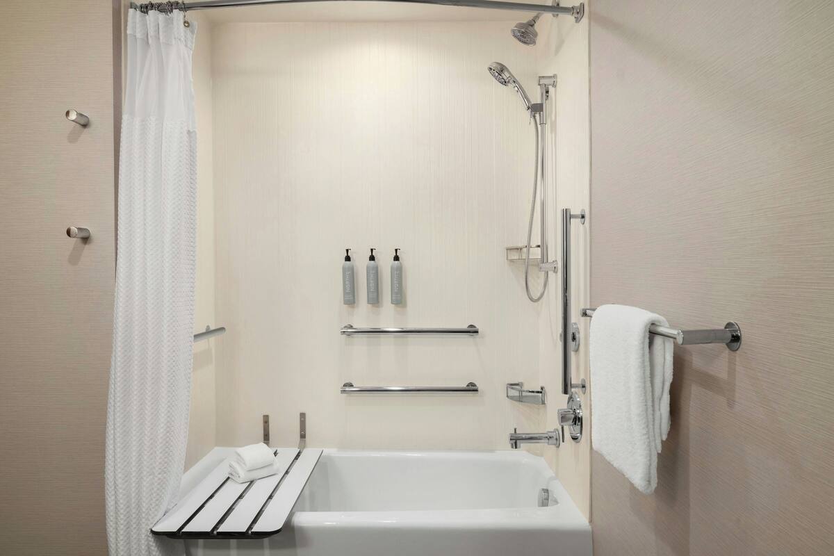 A modern bathroom with a bathtub, shower, and towel rack.
