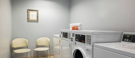 Une buanderie équipée de deux chaises, d’un lave-linge et d’un sèche-linge.