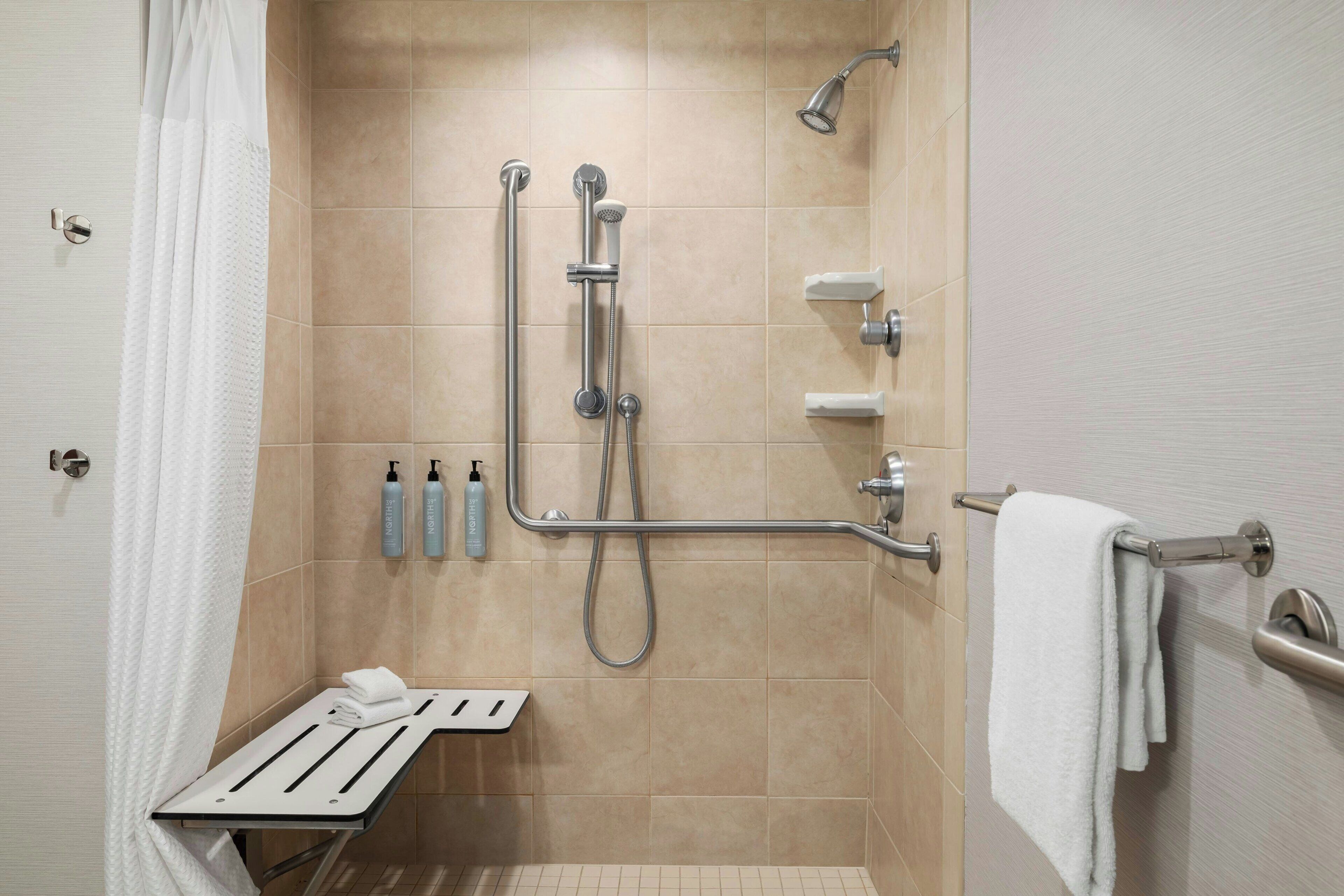 Un área de ducha moderna con cabezal de ducha manual, un accesorio de ducha manual y un perchero.