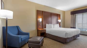 Relax in comfort with a large bed, a cozy armchair, and a small ottoman.