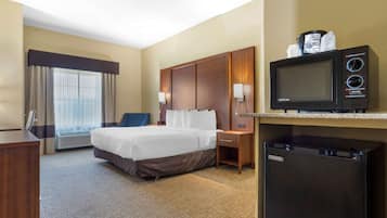 Una habitación de hotel con una cama, un escritorio, un microondas y un refrigerador.