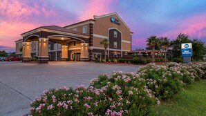 Un hotel Best Western con un diseño moderno, que cuenta con una entrada amplia, jardines ajardinados y un cielo despejado.