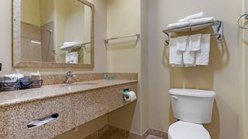A bathroom with a granite countertop, a sink, a mirror, a toilet, and towel racks.