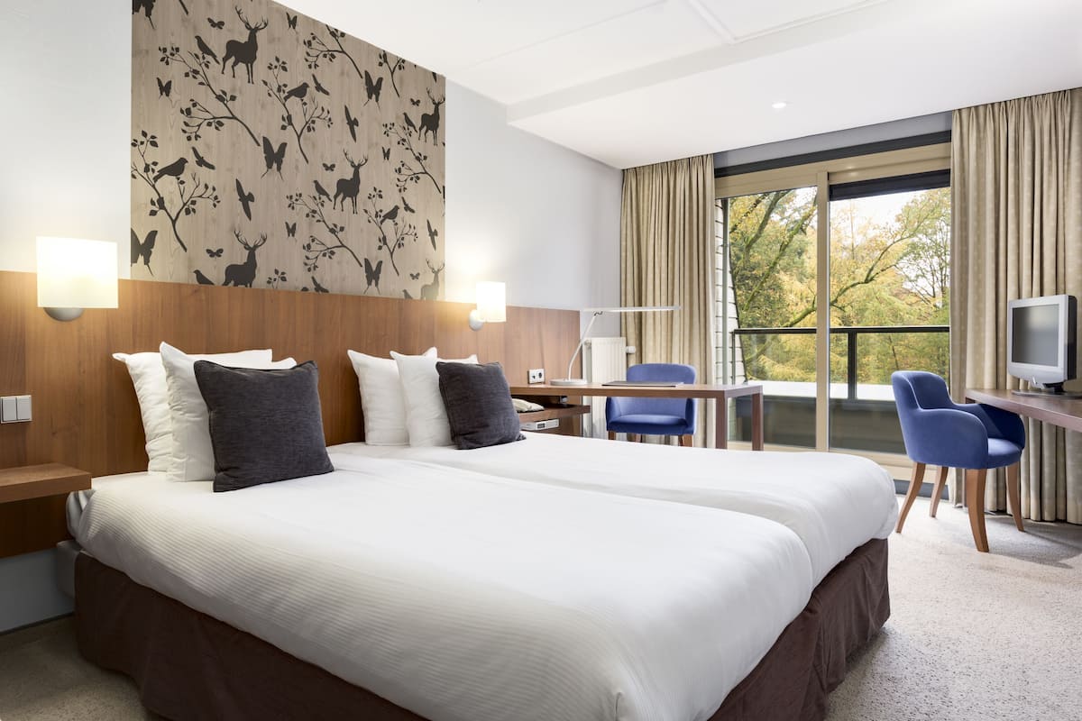 Habitación de hotel con una cama grande, un escritorio, una silla y un televisor.