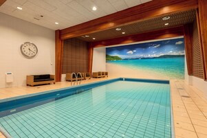 Una piscina con un mural de playa, techo de madera y un reloj en la pared.