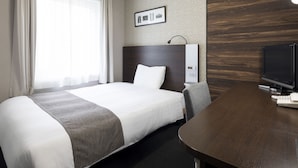 Une chambre d’hôtel équipée d’un lit, d’un bureau, d’une télévision et d’un panneau de commande fixé au mur.