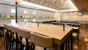 Une salle de conférence moderne dotée d’un plafond en bois, de plusieurs tables et de chaises.