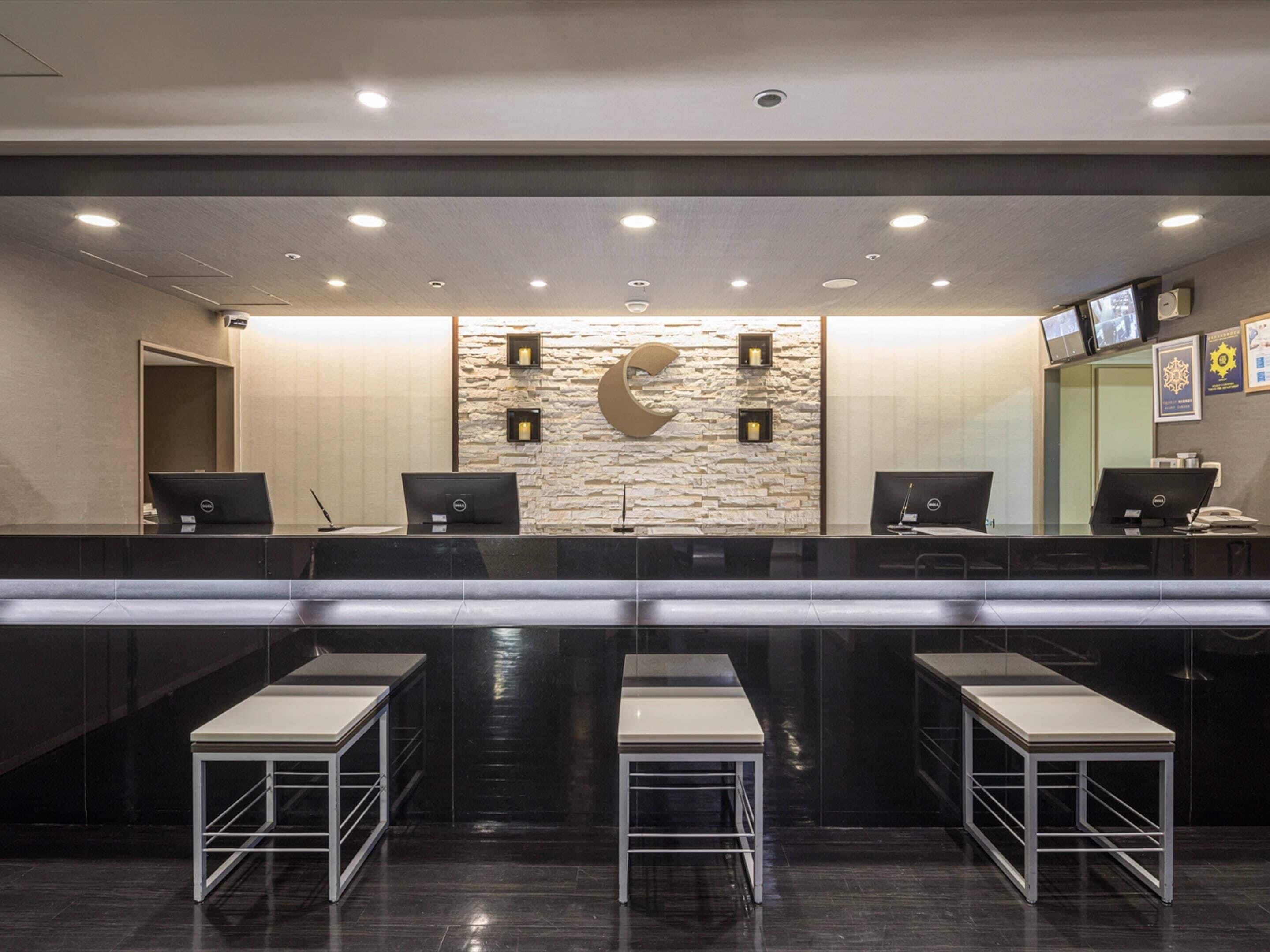 A reception area with a stone wall, three computer stations, and a seating area with tables.