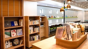L’intérieur d’une bibliothèque moderne, avec des étagères en bois, une table centrale servant de présentoir et des chaises vertes.