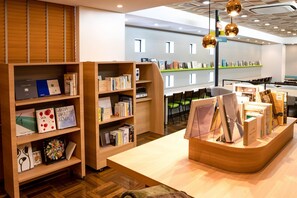 Interior moderno de biblioteca con estanterías de madera, una mesa de exhibición central y sillas verdes.