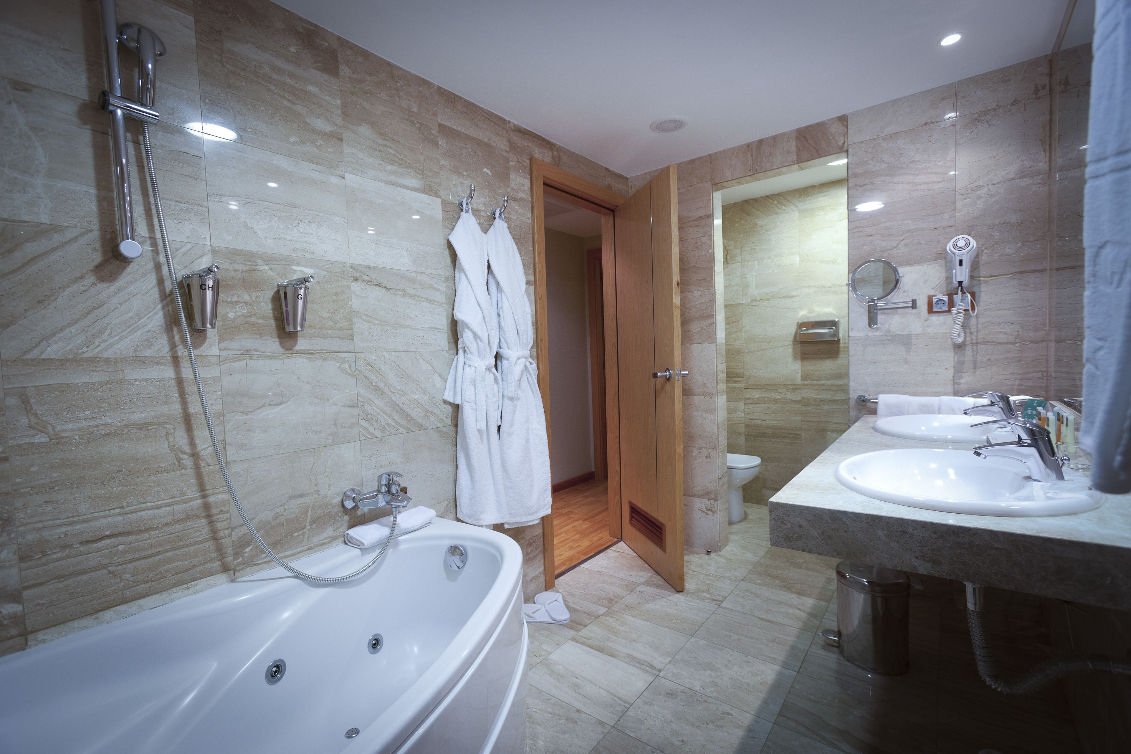 A modern bathroom with a bathtub, two sinks, a shower, and a mirror.