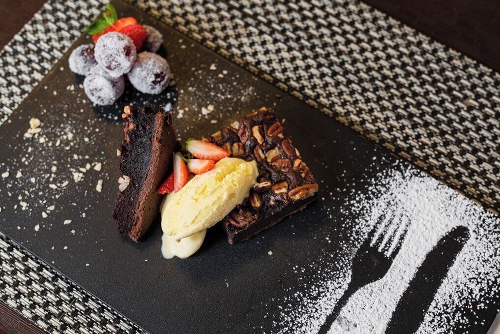 Um prato de sobremesa com bolo de chocolate, morangos e uma bola de sorvete.