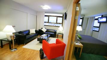 A modern living room with a black sofa, a red armchair, a coffee table, and a television on a stand.