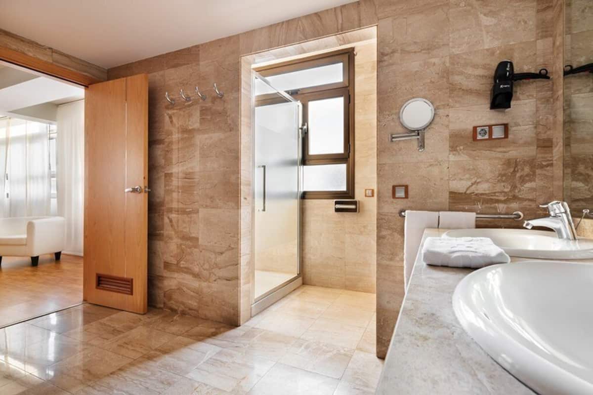 Ein modernes Badezimmer mit großem Spiegel, Waschbecken und Duschbereich.