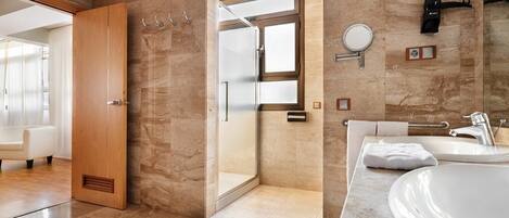 A modern bathroom with a large mirror, a sink, and a shower area.