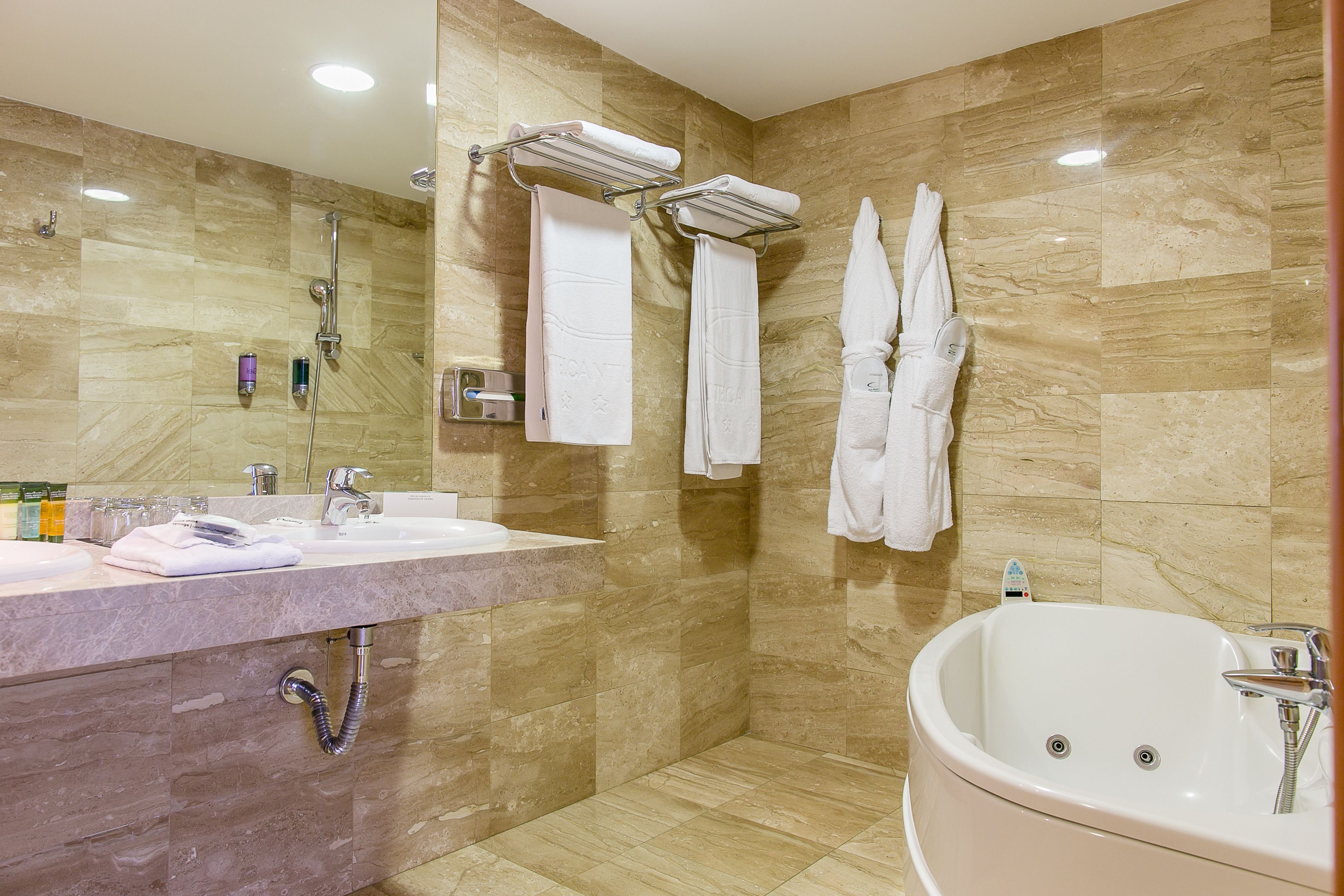 A modern bathroom with a marble sink, a large bathtub, and two towel racks.