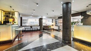 Eine großzügige Lobby mit Marmorboden, einer Rezeption, einer Sitzecke und großen Fenstern.