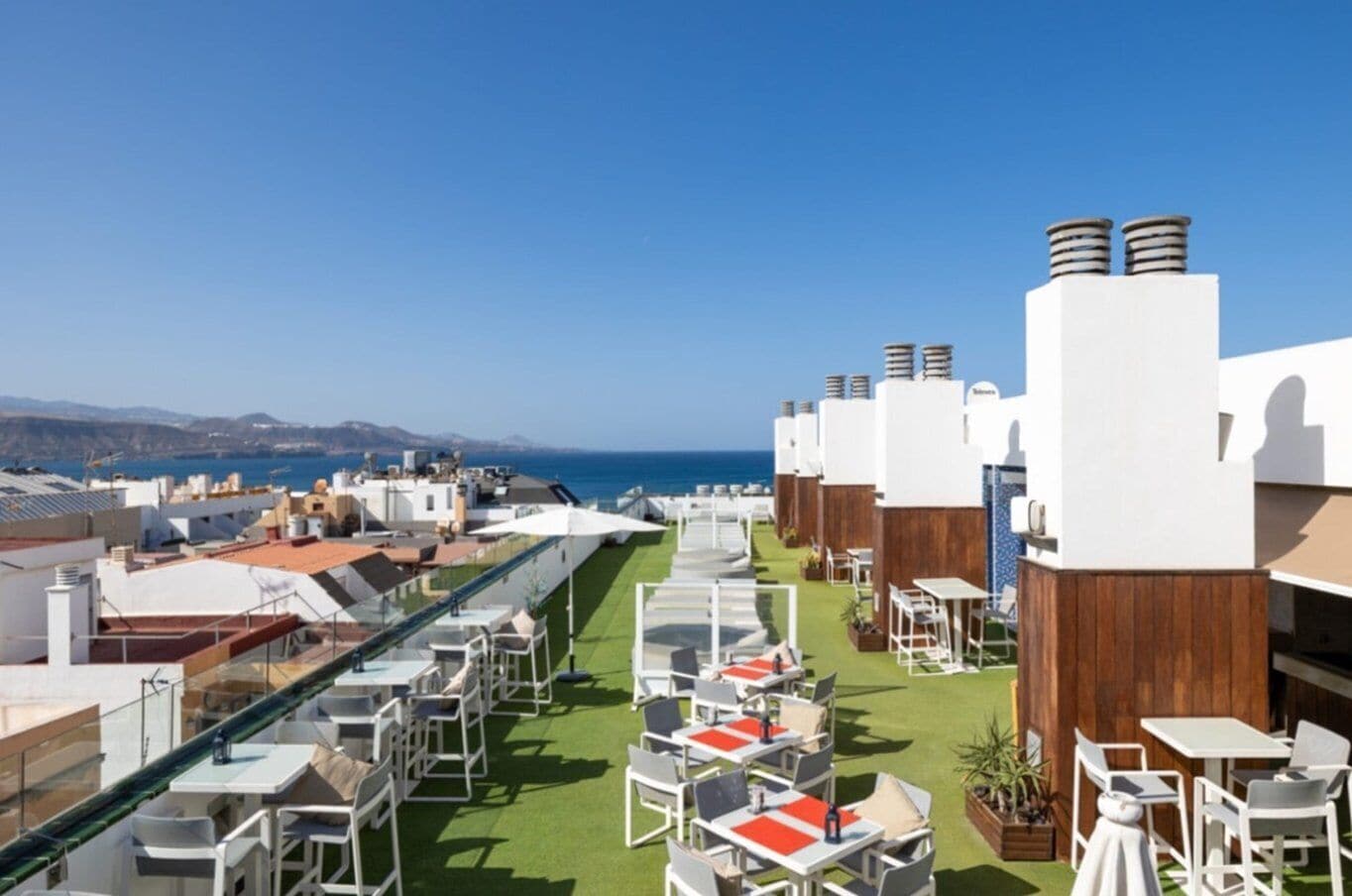 A rooftop terrace with outdoor seating and a view of the sea.