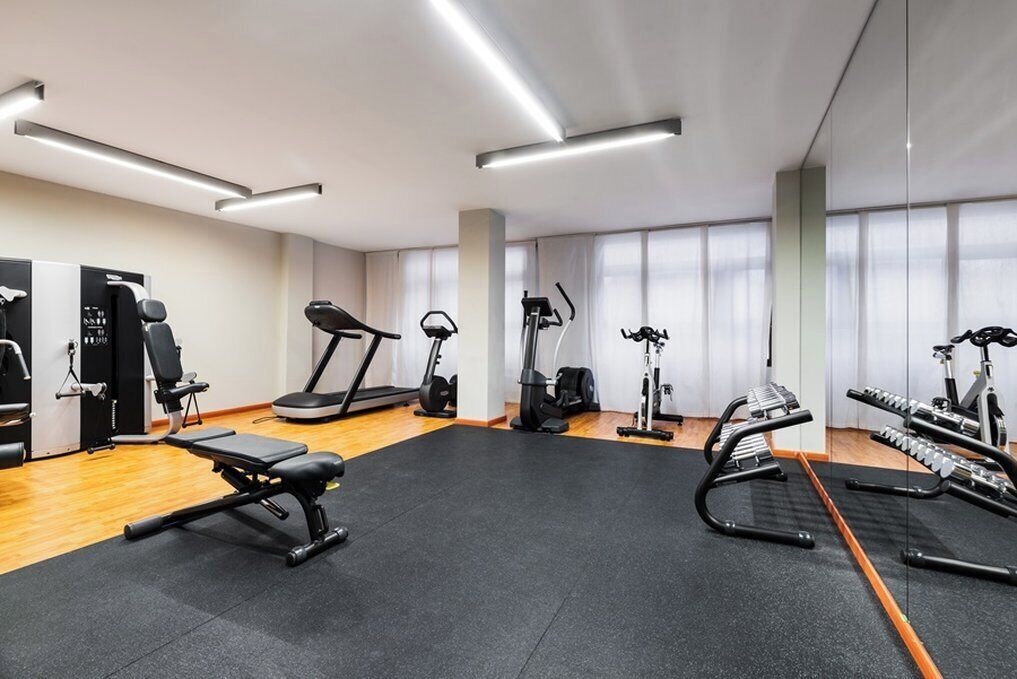 A modern gym with various exercise equipment, including treadmills, elliptical machines, and weight benches.