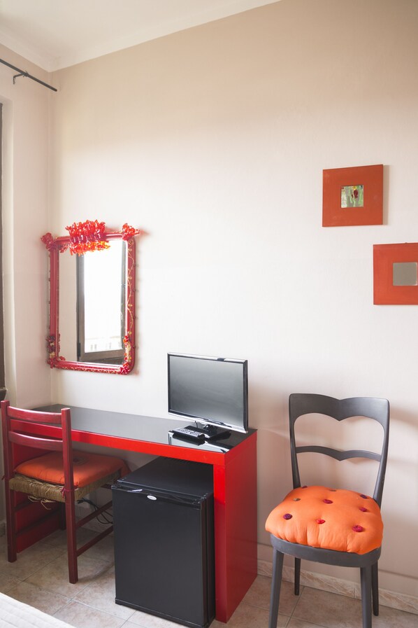 A compact room with a desk, a chair, a small refrigerator, and a mirror. - Hotel Panorama (Florence)