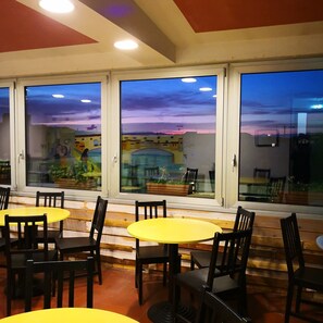 A restaurant with large windows offering views of a cityscape at dusk.