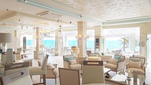 A spacious, elegantly decorated lounge area with comfortable seating and a glass table displaying various items. - El Oceano Beach (Mijas)