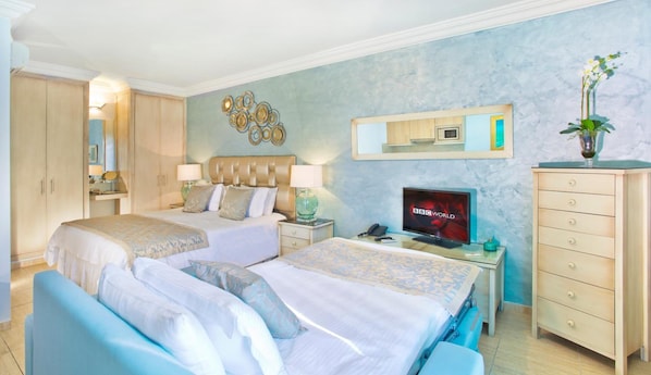 A hotel room with two beds, a television, a dresser, and a mirror. - El Oceano Beach (Mijas)