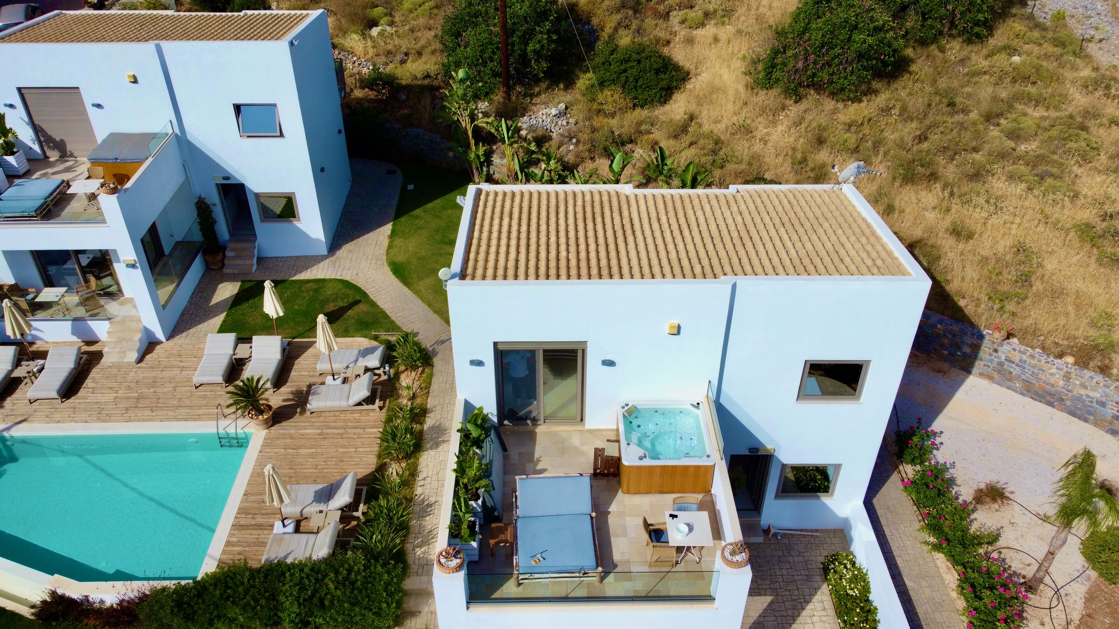 A modern two-story house with a swimming pool, outdoor seating, and a hot tub.