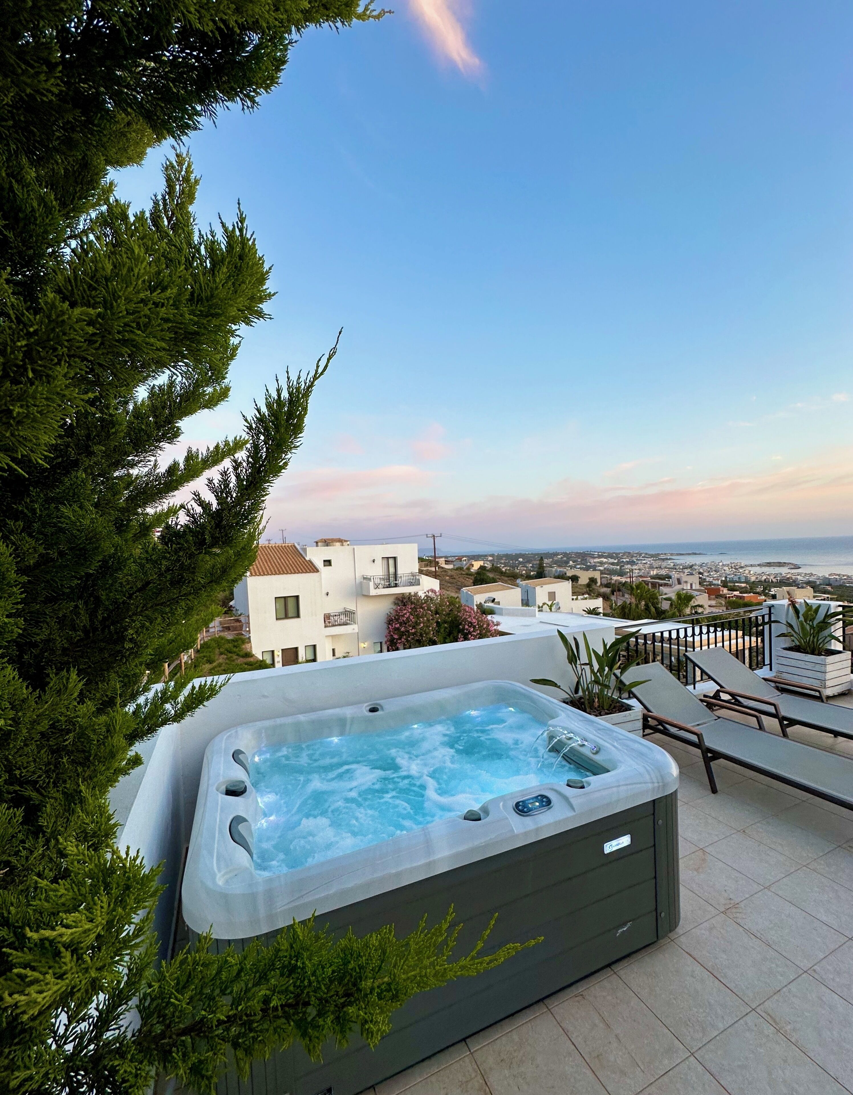 Un jacuzzi sur un toit, avec vue sur les bâtiments et la mer.