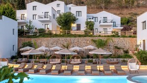 Un resort moderno con zona de piscina, mobiliario exterior y edificios blancos con balcones.