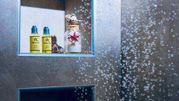 Un baño con un espejo que refleja tres botellas de champú Naturelle y un frasco decorativo con una estrella de mar.