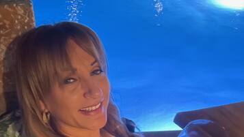 A person holding a glass of wine in a room with a pool in the background.