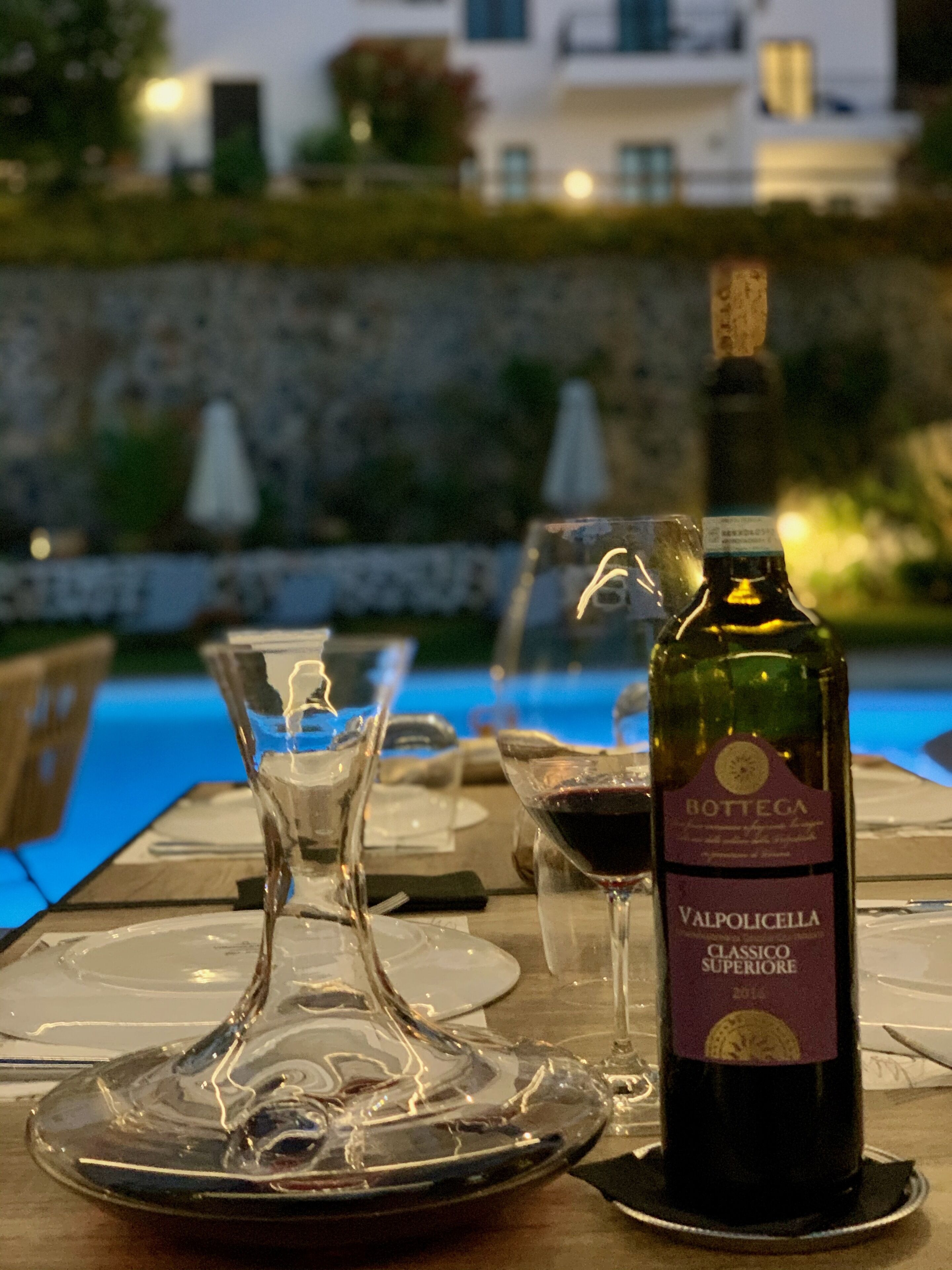 Een gedekte tafel voor een diner, met een fles Valpolicella wijn, een glas en een wijnglas.