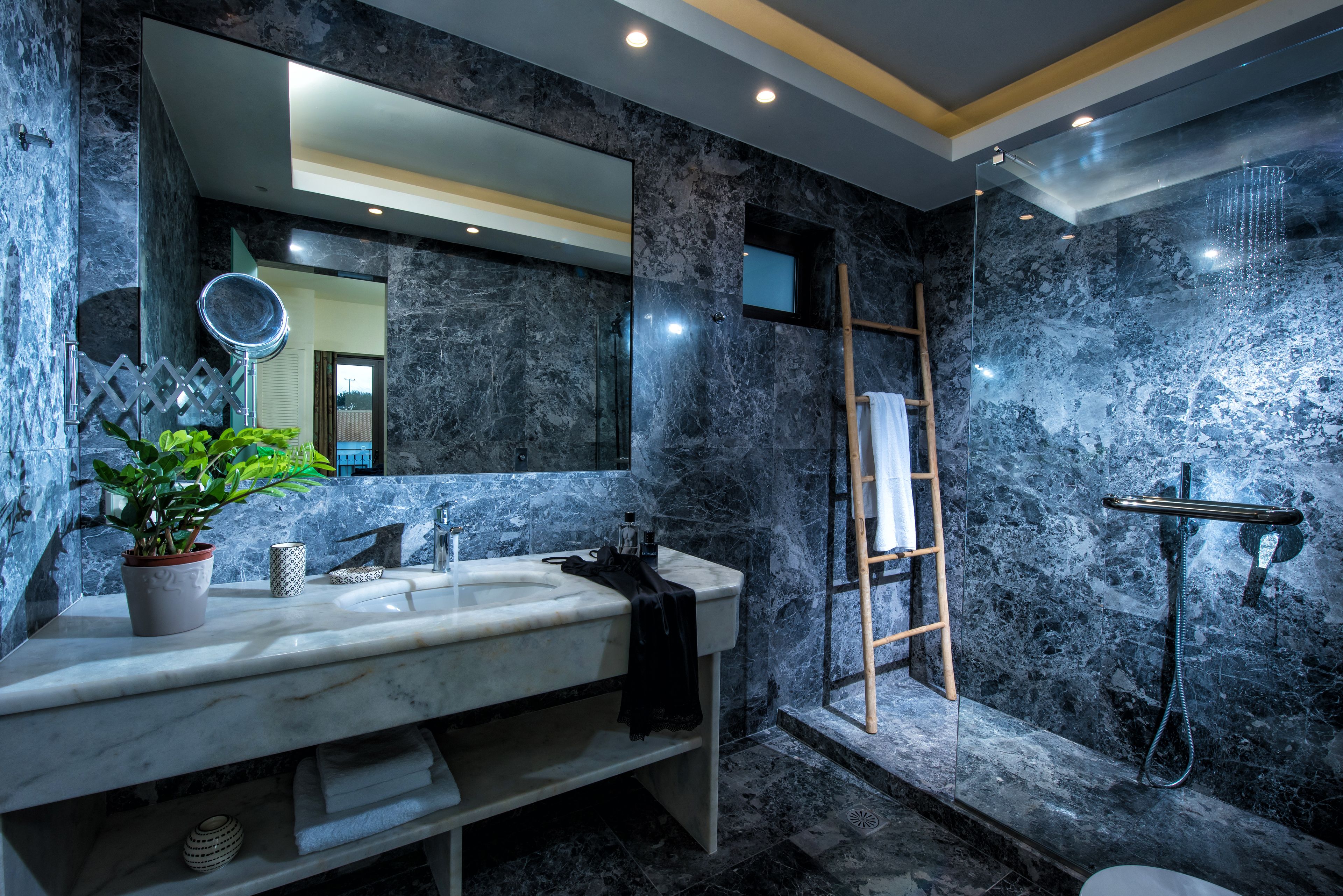 A modern bathroom with a marble sink, a large mirror, and a shower area.