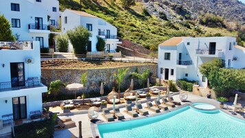 A resort with a pool, outdoor seating, and white buildings with balconies.