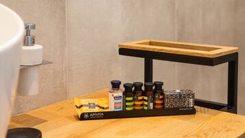 A wooden tray with various toiletries on a bathroom counter.