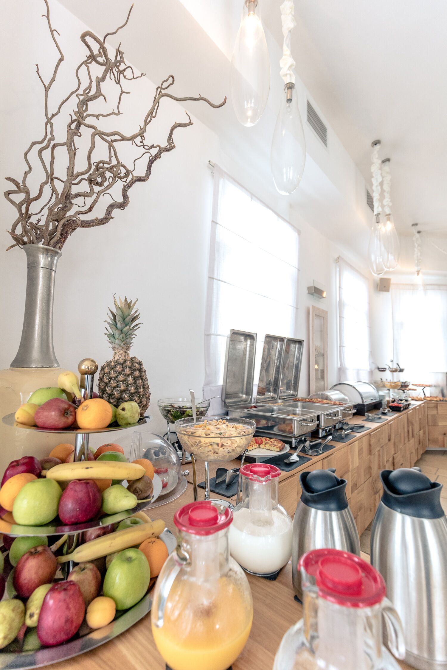 A buffet setup with various fruits, beverages, and hot food stations.