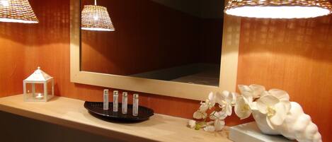 A bathroom vanity with a mirror, a small white lantern, and a black tray holding four candles.