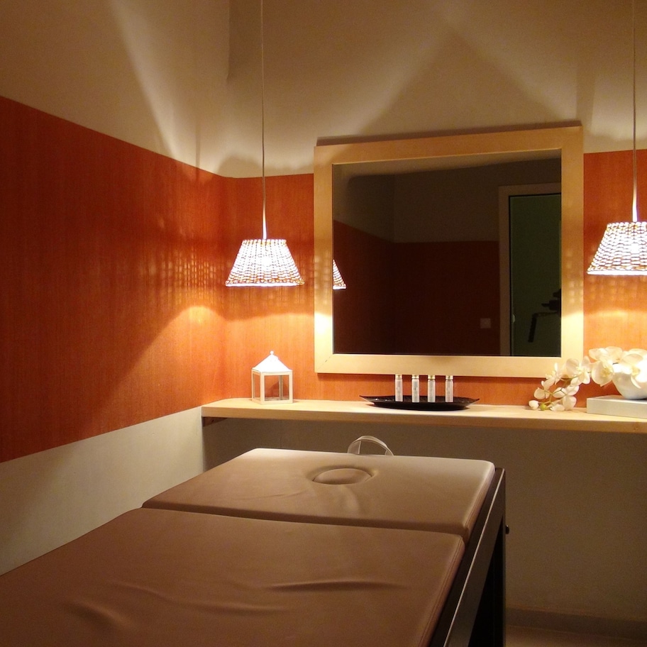 A hotel room with a bed, a vanity with a mirror, and two pendant lights.