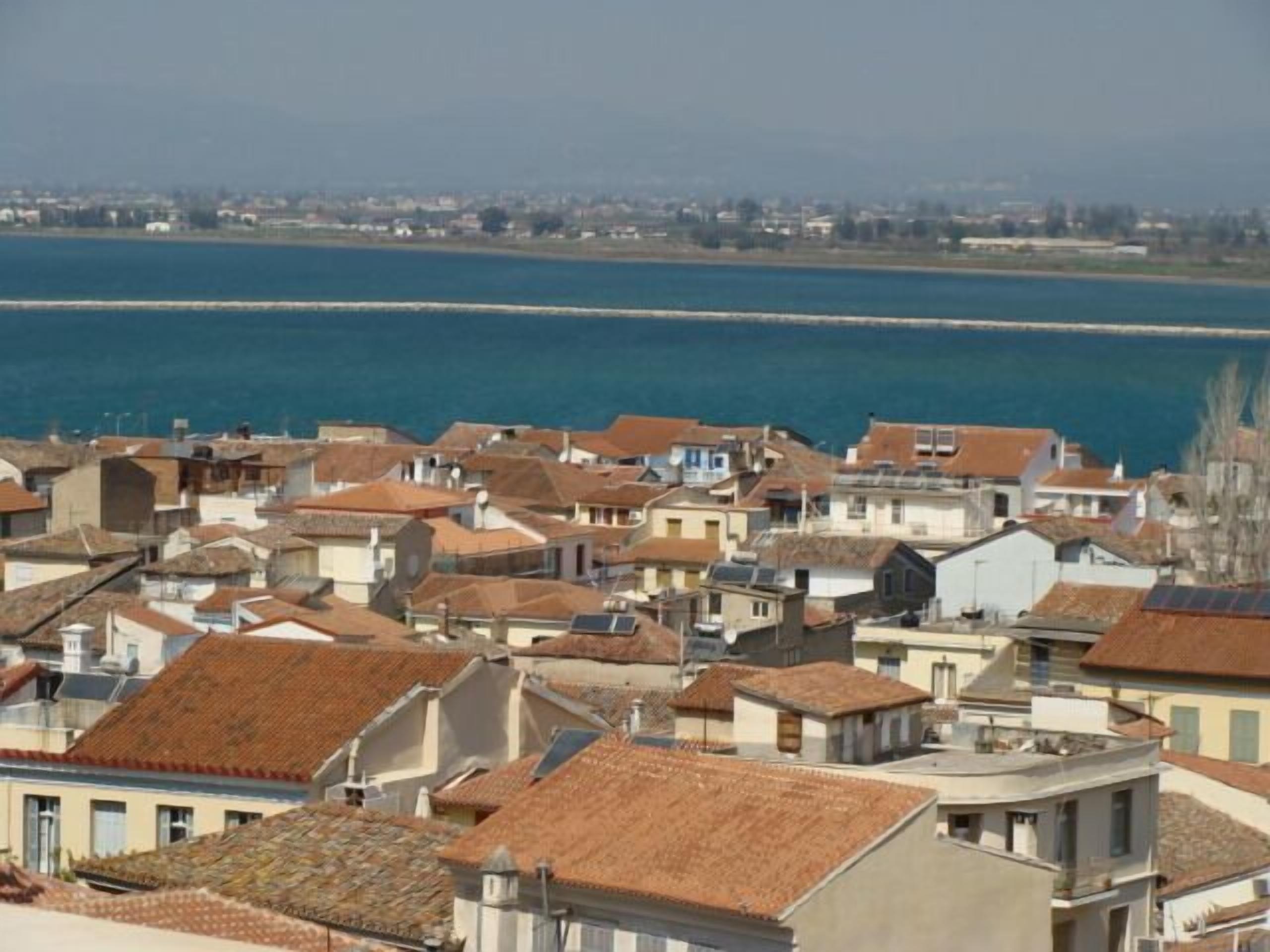 Un poble costaner amb edificis molt a prop els uns dels altres, alguns amb panells solars visibles, i una vista clara del mar.