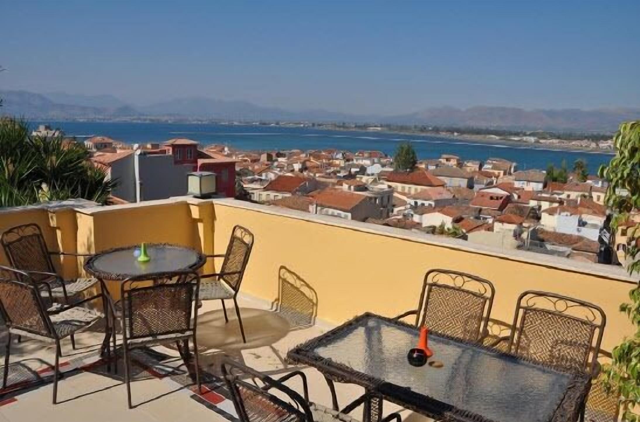 A terrace with a table and chairs overlooking a coastal town.