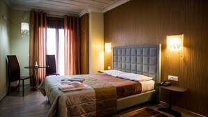 Habitación de hotel con cama, escritorio, silla, alfombra y dos lámparas de pared.