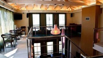 Una habitación de hotel con balcón, un ventanal grande y una lámpara colgante.