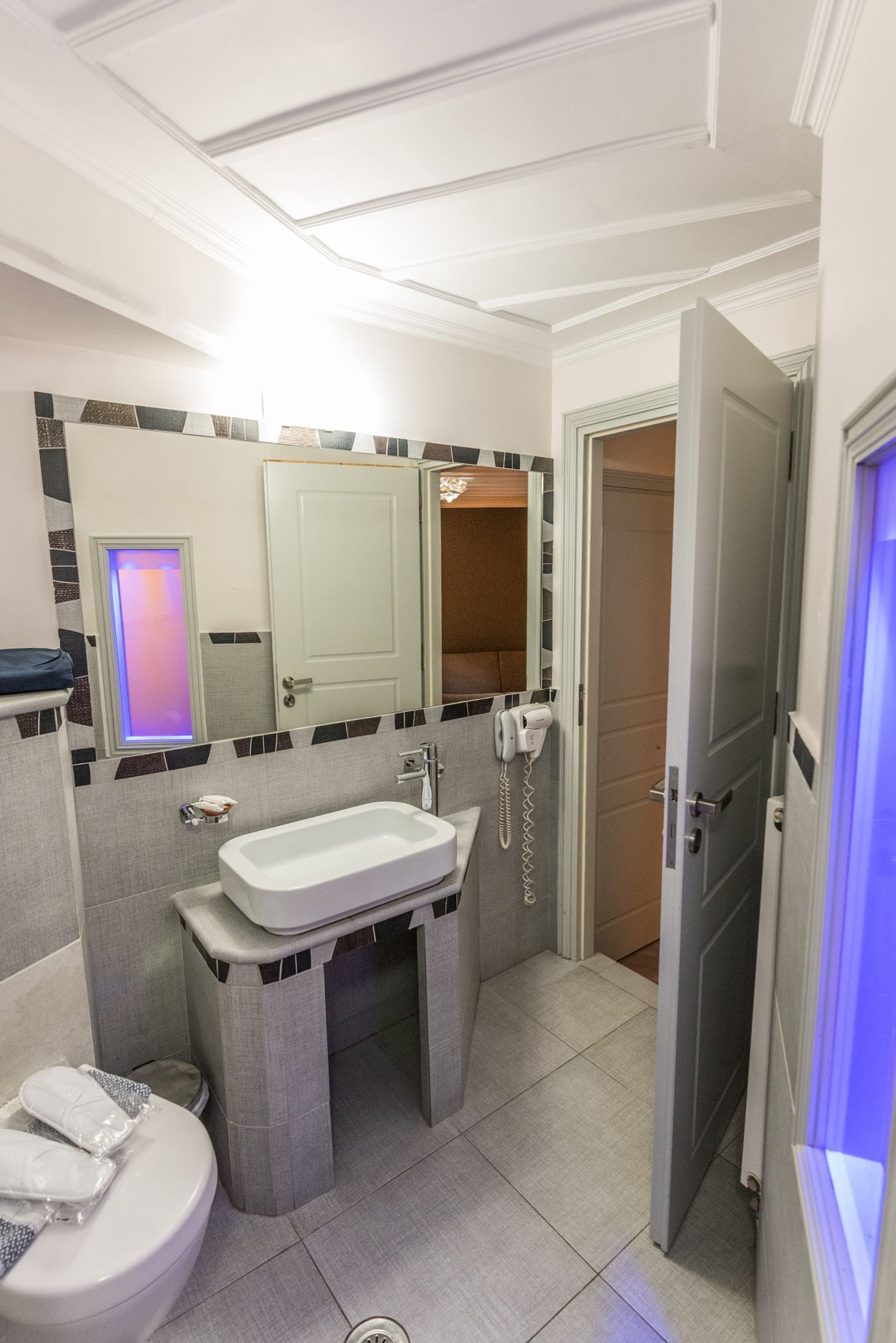 A modern bathroom with a white sink, a mirror, a toilet, and a shower area.