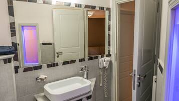 A modern bathroom with a white sink, a mirror, a toilet, and a shower area.